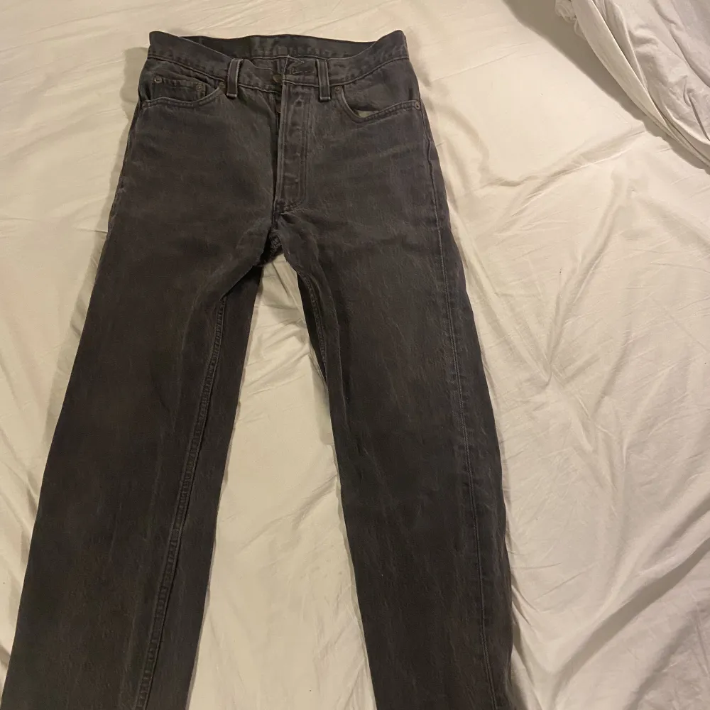 Ett par mörkgråa Levis 501 jeans i storleken W29 L30. Lägre pris eftersom det finns en del slitage i skrevet men notera att det blivit lappat och lagat. Denna modell är unisex, snygg och har hög kvalitet.. Jeans & Byxor.