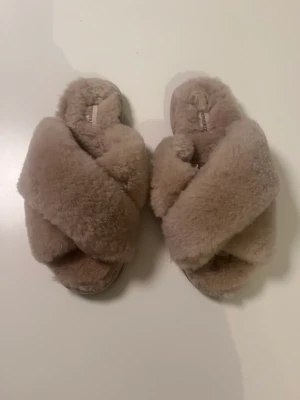 Shepherd tofflor strl 36 - Knappt använda, pga för liten storlek. Fint skick som ni kan se på bilden.   Varma och sköna damtofflor från Shepherd. Tofflorna är gjorda i äkta fårskinn i färgen ”Honey”. Slip-in modell som är lätt att ta på sig. Tofflorna är utrustade med yttersula. 