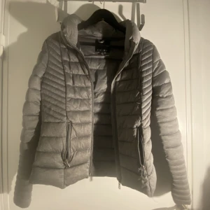 Grå höst/vinterjacka - Sparsamt använd jacka. Lite missfärgad på dragkedjorna.  Billigt pris pga deffekterna. Säljer pga för liten. Köpt för 349. 