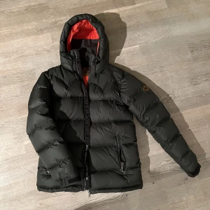 Jacka Jackson Hole unisex  - Superfin varm vinterjacka i mkt gott skick! Inköpt för ett par år sedan men sparsamt använd.  Mörkgrön med oranget foder.   Saknas endast skinnflärp på dragkedjan.   ORDINARIE PRIS 3700kr!  