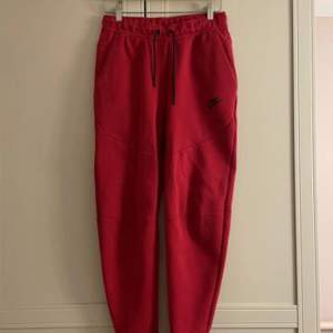 En röd nike tech fleece byxor, storlek S men passar M. Pris kan diskuteras köpt för 1100kr av JDsports, skicka för fler bilder. 