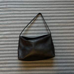 Liten väska i läder från Massimo Dutti, inköpt för 999kr. Är en utgången version av väskan på bilden. Matt svart läder. Ett innerfack. Fint skick men har tecken på användning. 