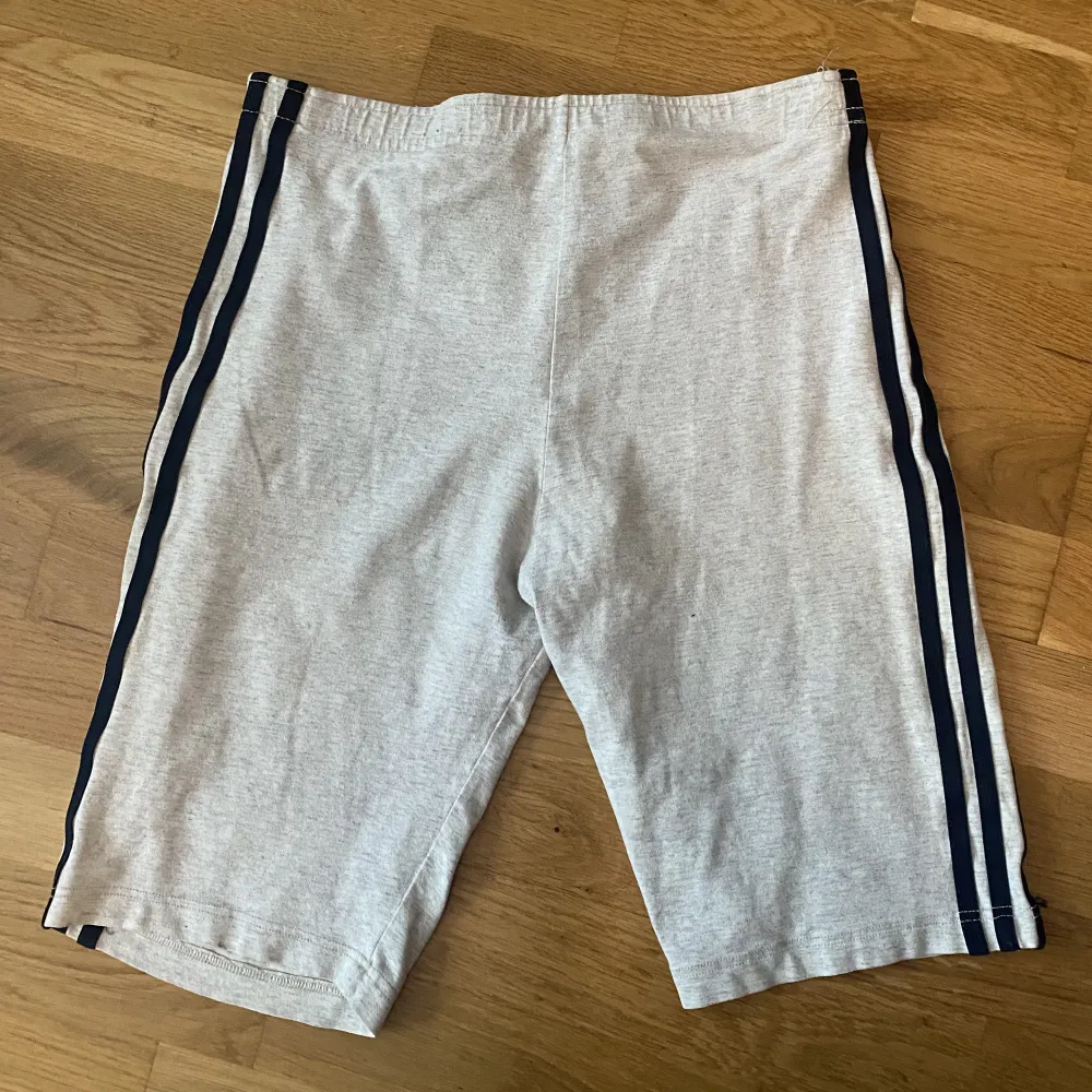 Gråa adidas cykelbyxor med blåa ränder. Sitter tight. Använda många gånger men ändå fina. Skriv för bild på 🤍. Shorts.