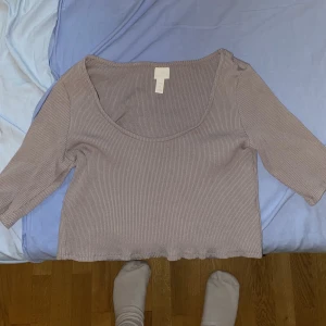 Kortärmad Grålila Topp - En grålila topp i storlek L från H&M! Jag trivdes i den i början men jag är en stor tjej med en snygg men stor mage, så toppen åkte upp konstant vilket störde mig!🥲 Annars älskade jag verkligen den här toppen! 