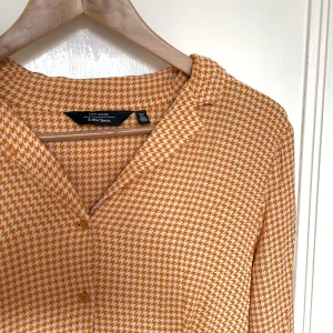 Orange klänning  - Orange hundtandsmönstrad klänning med en gammaldags vibe från & Other Stories i storlek 38. 