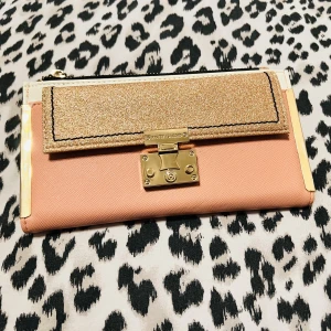Dam plånbok från River island - Superfin dam plånbok från River island.  Färg rosa, med glitter på framsida.  Insida vit med rosa glitter.  Flera fack och ytrymme finns.   Ny då den inte använts alls.   ”Pris går att pruta” 