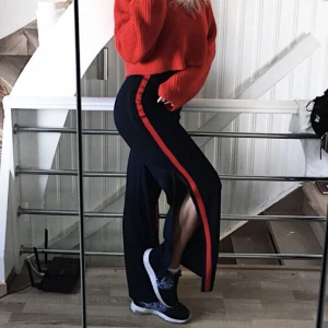 Vida byxor - Svarta vida byxor med en klarröd rand och slits på utsidan. Knappt använda så i nyskick! Storlek S. Jag är 168cm. (Andra bilden är lånad). Nypris 499kr, säljs för 100kr + frakt🥰