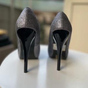 Nya klackskor stl 36 - Nya oanvända klackskor i stl 36. Prislappen sitter kvar. Silver glitter.