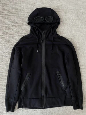 CP Company hoodie - CP company hoodie från Care Of Carl. Använd 3-5 gånger inga synliga defekter använd varsamt o äkta såklart INGET fake här hörru DU! Har digitalt kvitto och tags/extra knappar kvar. Kom dm för frågor och funderingar 