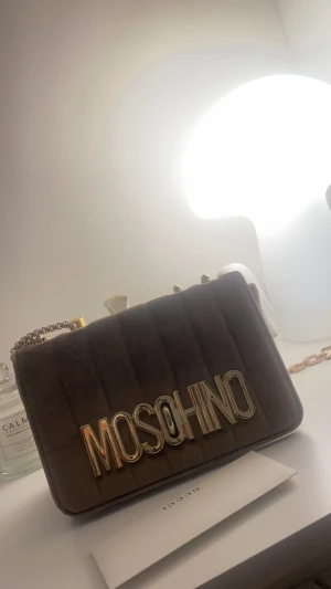Moschino väska oanvänd - Moschino väska i beige/guld  Oanvänd men inget kvitto då den var en present, därav priset 