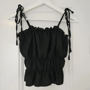 Topp - Snygg topp som man själv knyter i axlarna. Aldrig använd och är i nyskick! Väldigt stretchig - passar nog xs/s/m