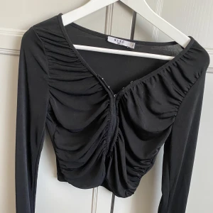 Svart NA-KD topp - Aldrig använd topp från NA-KD  Storlek Medium.  Knäppen längs hela tröjan väldigt skygg