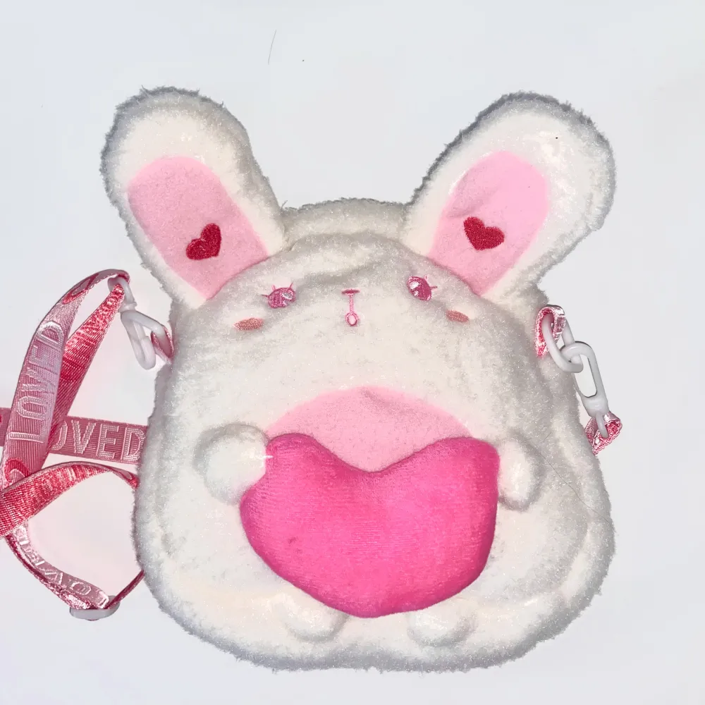 Liten handväska i form av en kanin med rosa gulliga detaljer. Bara andvänd en gång och säljer den då det inte längre är min stil. Den rymmer ungefär en mobil och en lite plånbok . Väskor.