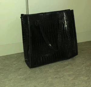 Väska - Svart väska i ormskinnsmönster. Mycket bra skick. Rymmer mycket, passar perfekt till skola eller kanske gym.
