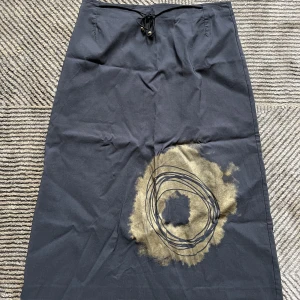 Grå långkjol med mönster - Grå långkjol med mönster i st 38 från märket IMITZ. Kjolen har även ett snöre med guldpärlor på i midjan och gömd dragkjedja där bak.  Pris 100kr