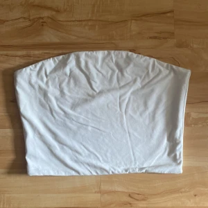 Tubtopp - Vit tubtopp från bikbok. Använd fåtal gånger och är i storlek L. Har en sorts gummirem på framsidan av toppen för att hålla sig på plats vid användning! 150kr+frakt