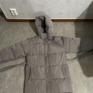 Long puffer jacket  - Lång fodrad och vadderad jacka. Dragkedja och tryckknappsstängning. Skärp i midjan. Fickor där fram. Använts max 5 gånger. Köpt för 999kr.