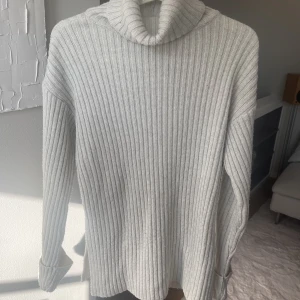 Beige/ljusgrå stickad tröja NA-KD - Lång stickad tröja med polokrage, sydda uppvikta långa ärmar och slits i sidorna från NA-KD