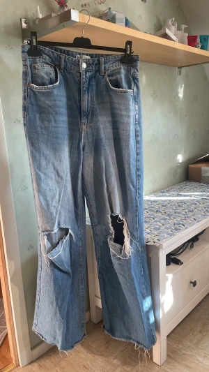 jeans - Vida jeans med hål över knäna. De är vida och highwaist passar inte längre. Det är något kortare mot de i butik då jag klippte av de för de var för långa  storlek 40 från ginatricot 