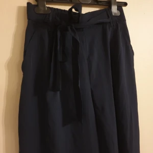 Culotte byxor - Mörkblå. Vida, luftiga byxor med knytning i midjan. Vadlånga i culotte-stil.