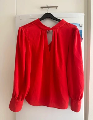 River island blus röd/orange - Vad: Tröja i orange/röd färg. Märke: River island  Storlek: 36 (UK 10) Material: 100 % polyester Skick: Oanvänd