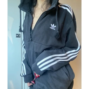 Adidas Hoodie - Hoodie från Adidas Originals, "munkficka" alltså du har båda händerna i en stor ficka med dragkjedjor på båda sidorna (bild2). Köpte denna hoodie för att användas oversized 😛 rikigt mysig och varm tröja som även går upp en den till halsen 🤩