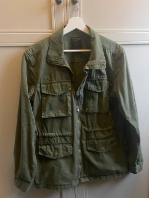 Grön jacka - Perfekta höstjackan! Snygg grön färg. Går att dra åt resår i midjan. Använd fåtal gånger, väldigt bra skick!