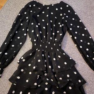 Känning - Prickig klänning med resor i midjan och även volanger längst ner i 3 lager. Använd en gång