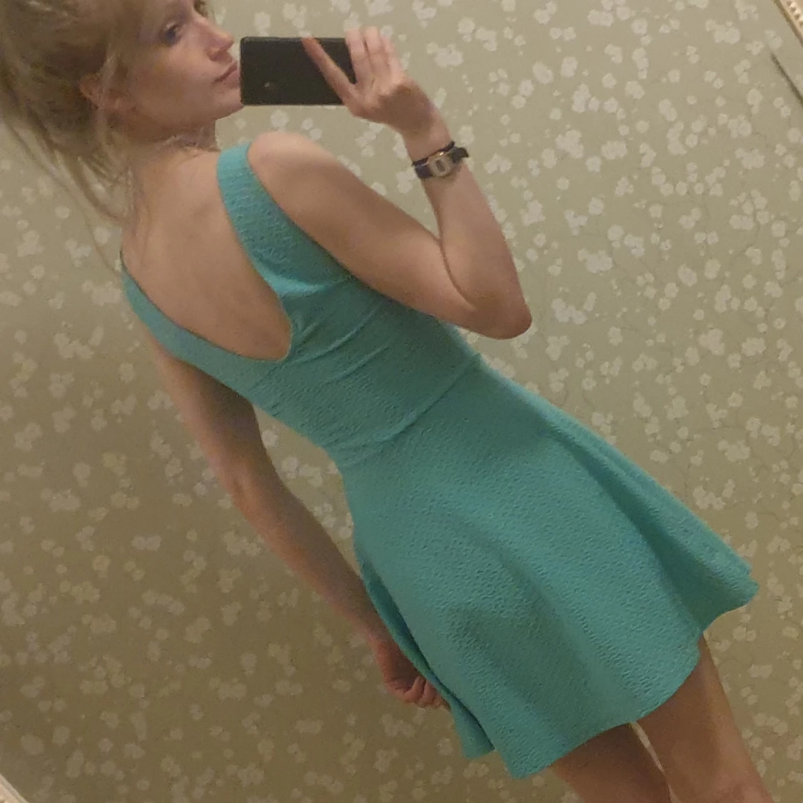 Turkos miniklänning med strukturvävt tyg och öppen rygg.