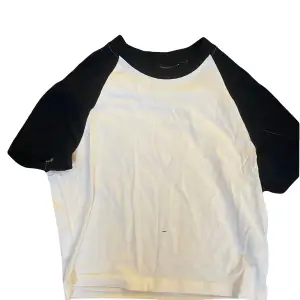En vit T-shirt med svarta ärmar och halsmudd som är super bra skick! 