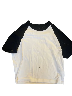 Svart och vit T-shirt - En vit T-shirt med svarta ärmar och halsmudd som är super bra skick! 