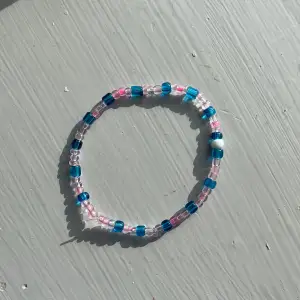 Supersnyggt armband som är blått och rosa med en vit pärla i mitten som jag har gjort✨