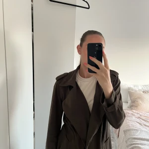 Kappa trenchcoat i fakemocka - Fin kappa i trenchcoatmodell i mörkgrön fakemocka. Mjuk och skön och värmer en del. Passar bra som höst och vårjacka 