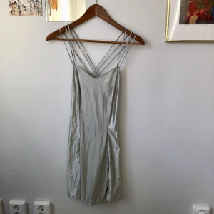 Kort skimrande klänning med flätad rygg - Fantastisk, kort, skimrande klänning med flätad rygg! Färgen är mer mintgrön i verkligheten. Vackra sömmar och fin ringning. Skulle gissa på storlek XS/S🦋