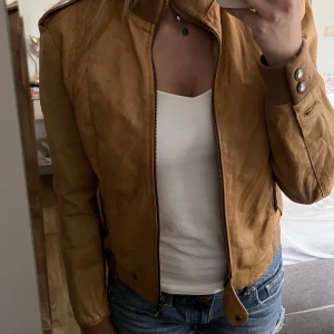 Brun läderjacka - Brun läderjacka i fejkläder. Begagnat skick, saknas knappar vid ärmsluten, ena flärpen på axeln har lossat och jackan har några mindre omärkbara fläckar. Storlek 44/L men sitter mer som en 38/M eller 36/S 🫶💕