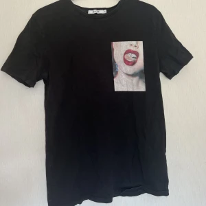 T-shirt med tryck - En svart T-shirt med tryck i storlek XS från Nakd. Relativt använd och trycket är lite halvt slitet (se ovan). Relativt figurnära material och har tyvärr växt ut. Köpt för ca 300kr.