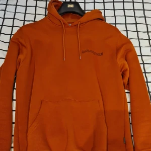 Orange hoodie  - Orange hoodie med litet tryck på bröstet.