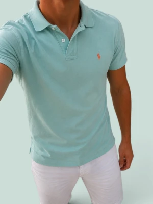 Ljusblå pikétröja från Polo Ralph Lauren - Snygg ljusblå pikétröja från Polo Ralph Lauren med klassisk krage och två knappar framtill. Tröjan har korta ärmar och den ikoniska loggan broderad på bröstet. Perfekt till jeans eller shorts för en clean och fräsch look.