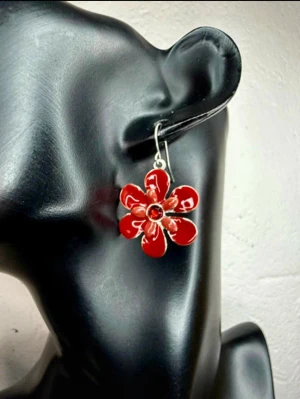 RubrikI.Me.My Röda Blomörhängen – Y2K Emalj & Strass – Guldfynd – Oanvända - Färgstarka blomörhängen från I.Me.My (Guldfynd), sannolikt från Y2K/tidigt 2000-tal. Röda emaljerade blommor med röd strass i mitten och silverfärgade krokar – perfekta till sommar, festival eller när du vill ge din outfit en lekfull färgklick. Ca 3,5 × 2,5 cm. Oanvända och sitter kvar på originalkortet. Nypris 89,50 kr. Jag prutar inte, men erbjuder bra bundlerabatt vid köp av flera föremål.