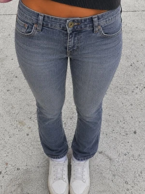 Blå bootcut jeans med låg midja - Säljer ett par klassiska blå bootcut jeans med låg midja och fem fickor. Jeansen har en lätt tvättad look och raka ben som smalnar av något. Perfekta till sneakers eller boots och passar till många olika stilar.