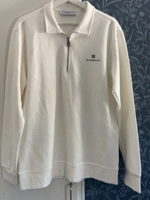 Vit halvzip tröja från Givenchy - Snygg vit långärmad tröja från Givenchy med halvzip och diskret logga på bröstet. Tröjan har krage och är tillverkad i mjukt material som känns lyxigt. Perfekt för dig som gillar stilrena och exklusiva plagg.