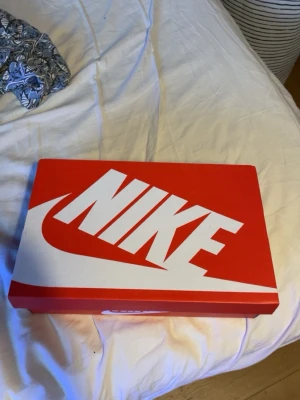 Svarta Nike sneakers med vit sula - Säljer ett par svarta Nike sneakers med vit sula och vit swoosh på sidan. Skorna har en sportig look med meshdetaljer och grov yttersula för bra grepp. Perfekta för dig som gillar stilrena och bekväma sneakers.