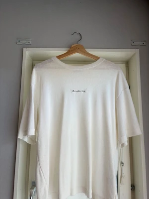 Vit oversized t-shirt med tryck - Säljer en vit oversized t-shirt med ett litet broderat tryck på bröstet där det står 'The creative living'. T-shirten har rund hals och avslappnad passform. Perfekt för en chill och stilren look.