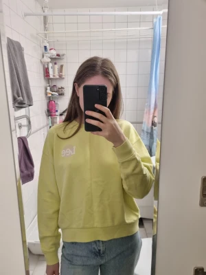 Gul sweatshirt från Lee - Säljer en ljusgul sweatshirt från Lee med broderad logga på bröstet. Tröjan har en avslappnad passform, rund halsringning och ribbade muddar vid ärmar och nederkant. Perfekt för en chill och stilren look.