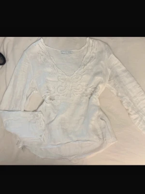 Vit linnetopp med paljetter & broderade blommor – stl L - Superfin långärmad linnetopp i vitt med vackra detaljer! Dekorerad med stenar, broderade blommor och fina paljetter som ger en exklusiv och feminin känsla. Perfekt till både vardag och fest – ett unikt plagg som verkligen sticker ut. Storlek L. Inga defekter. 