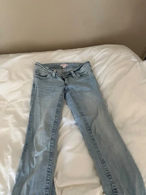 Ljusblå raka jeans med broderade fickor - Säljer ett par ljusblå jeans med raka ben och snygga broderade detaljer på bakfickorna. Klassisk femficksmodell med bälteshällor och knappgylf. Perfekta till en avslappnad look och passar till det mesta i garderoben.