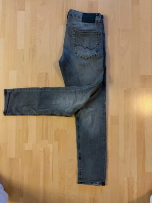 Jack & Jones Glenn slim fit  - Säljer ett par grå slim fit jeans med klassisk femficksdesign och svarta sömmar. Jeansen har en diskret tvättad look och raka ben. Perfekta för dig som gillar en enkel men snygg stil. W31 L32