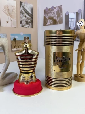 Jean Paul Gaultier Le Male Elixir - Jean Paul Gaultier Le Male Elixir parfym i en ikonisk flaska formad som en manlig torso i guld och mörkröda ränder. Flaskan har en metallisk finish och kommer med en lyxig guldfärgad cylinderförpackning med märkets logga på framsidan.