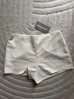 Vita högmidjade shorts Missguided - Snygga vita högmidjade shorts från Missguided. De har en clean look utan synliga detaljer framtill och lätt v-formad nederkant. Perfekta till sommaren och passar till allt från crop tops till oversized skjortor.