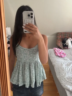 Grön topp  - Säljer en söt grön topp med vita blommor. Knyte där bak💕